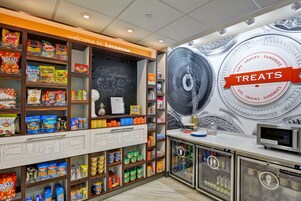 Exposição de petiscos e guloseimas com diversos produtos e uma lousa com a previsão do tempo.