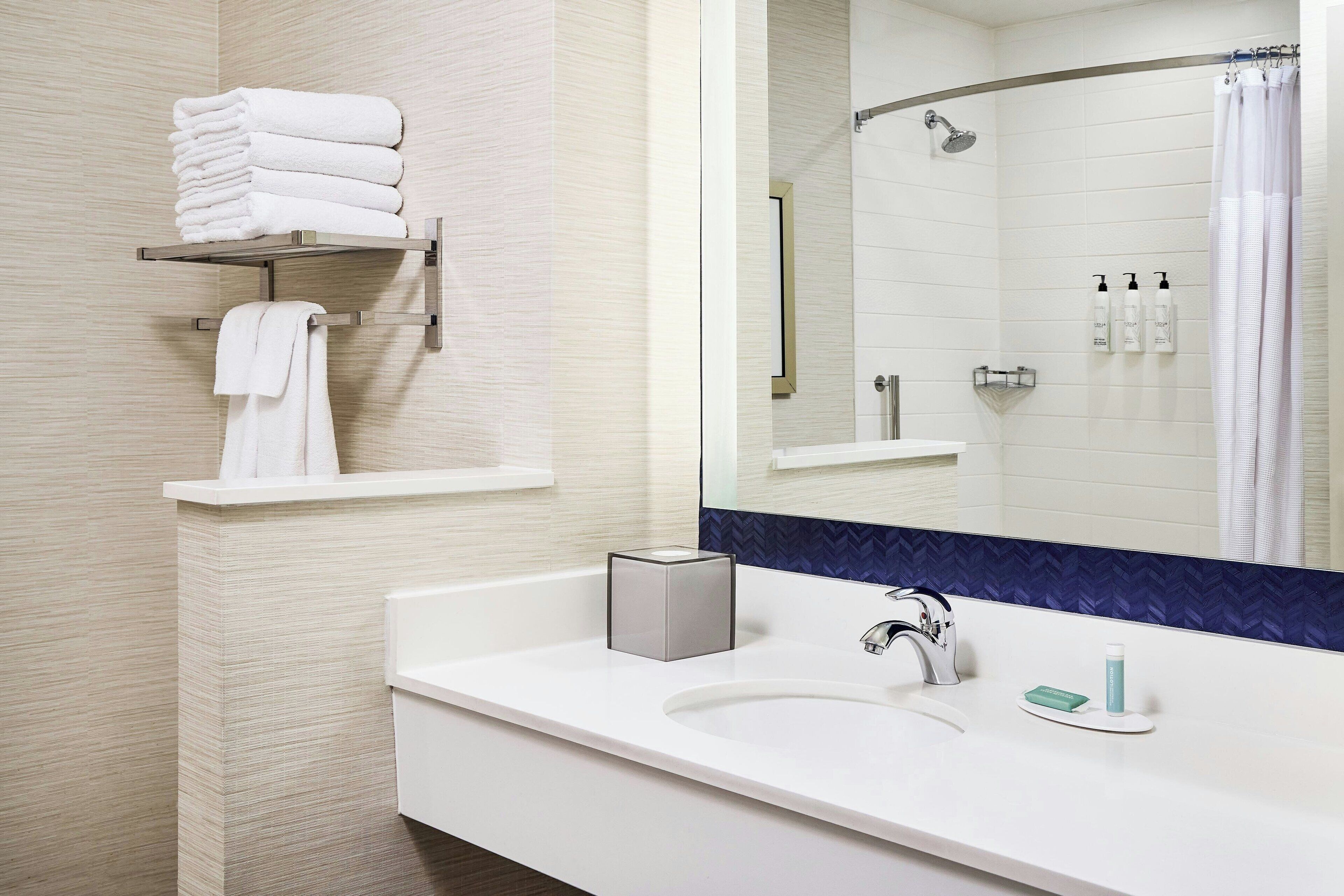Un bagno moderno con lavandino bianco, specchio e cabina doccia.