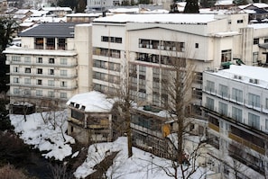 A multi-story building with a flat roof, several balconies, and a snow-covered ground.