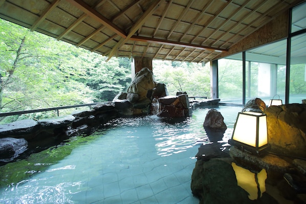 A tranquil indoor water feature with a wooden ceiling and large windows.