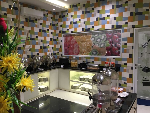 Una cocina moderna con un salpicadero de azulejos coloridos, un cuadro con motivos de frutas y un dispensador de agua.