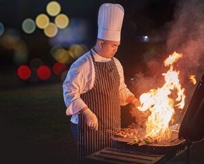 Um cozinheiro grelhando carne ao ar livre à noite.