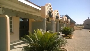 A row of buildings with a consistent architectural style, featuring arched doorways and columns. - Sahara Stones Hotel (Palapye)