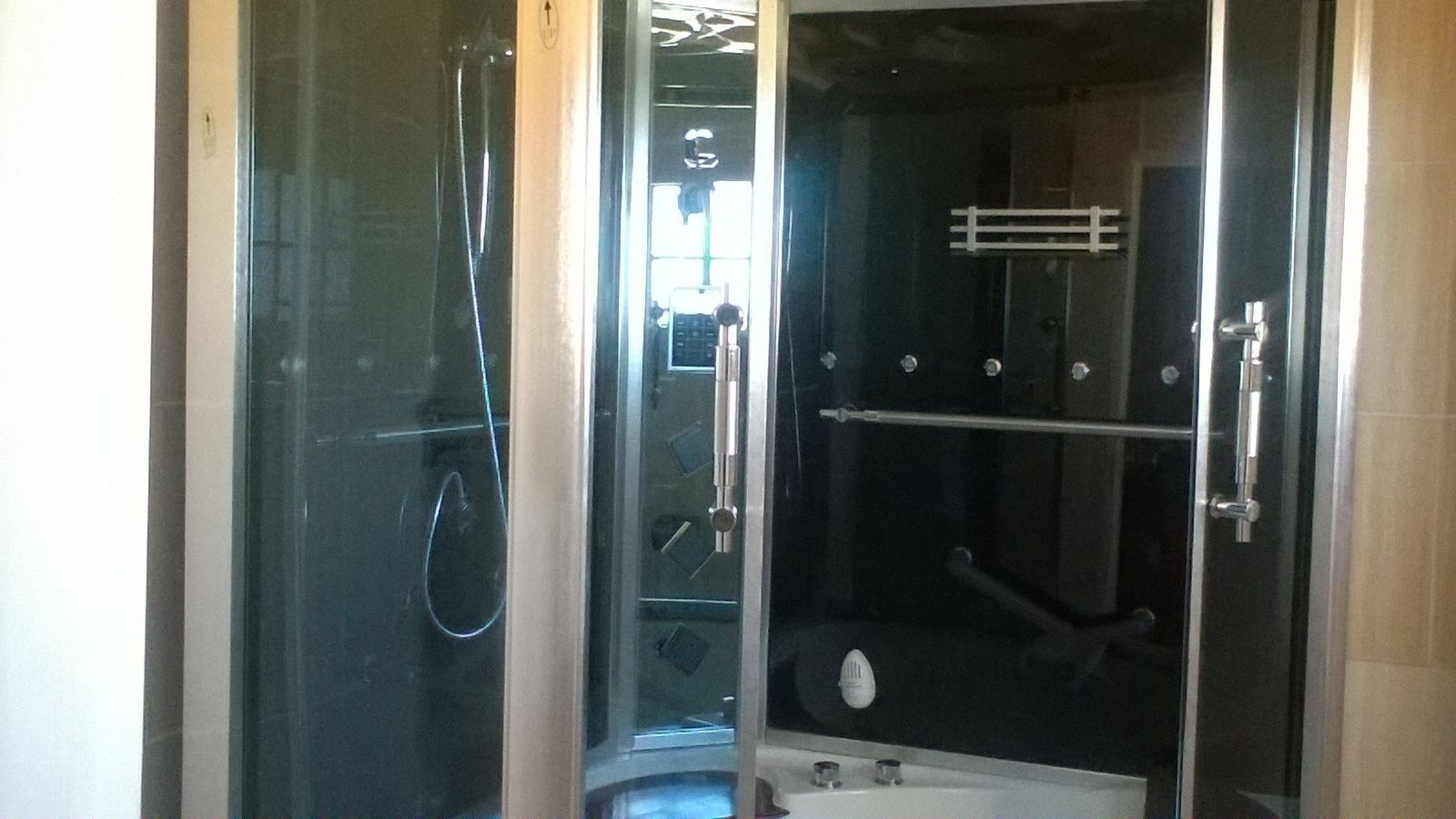 Un área de ducha con mampara de vidrio, una bañera, un perchero y un inodoro a la vista.