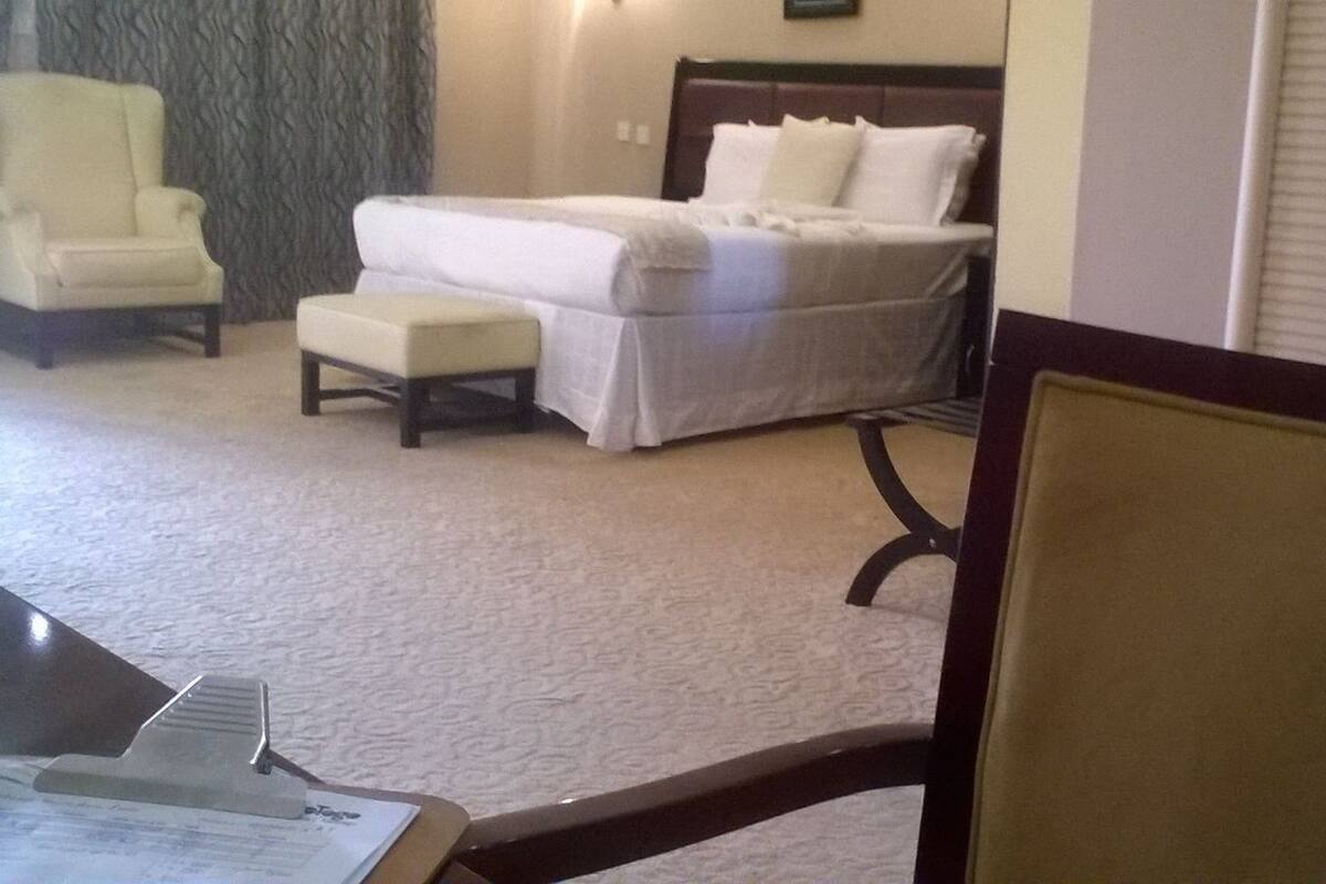 A hotel room with a bed, a chair, and a desk.