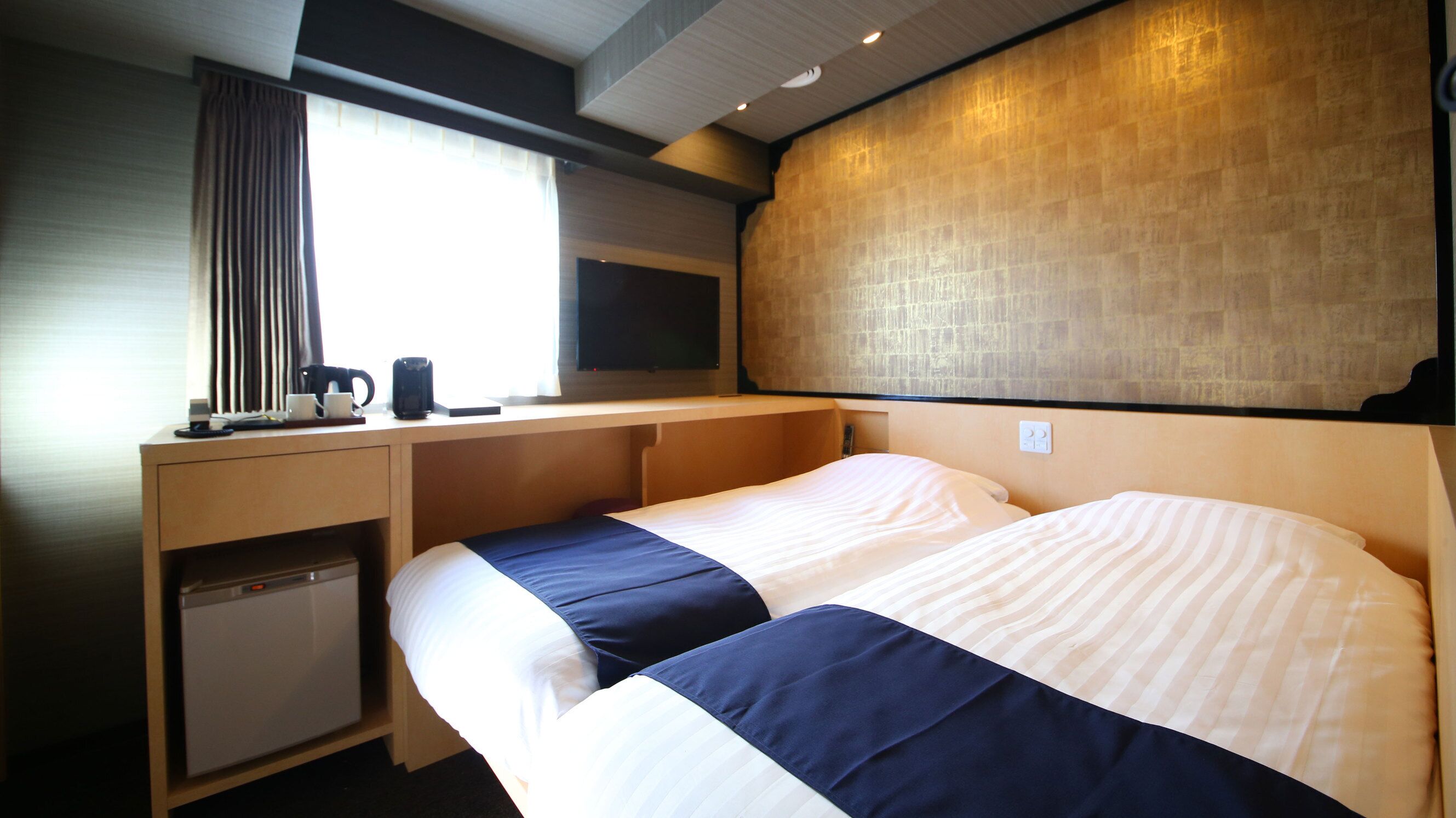 Une chambre d’hôtel équipée d’un lit, d’un bureau, d’une machine à café et d’une télévision.