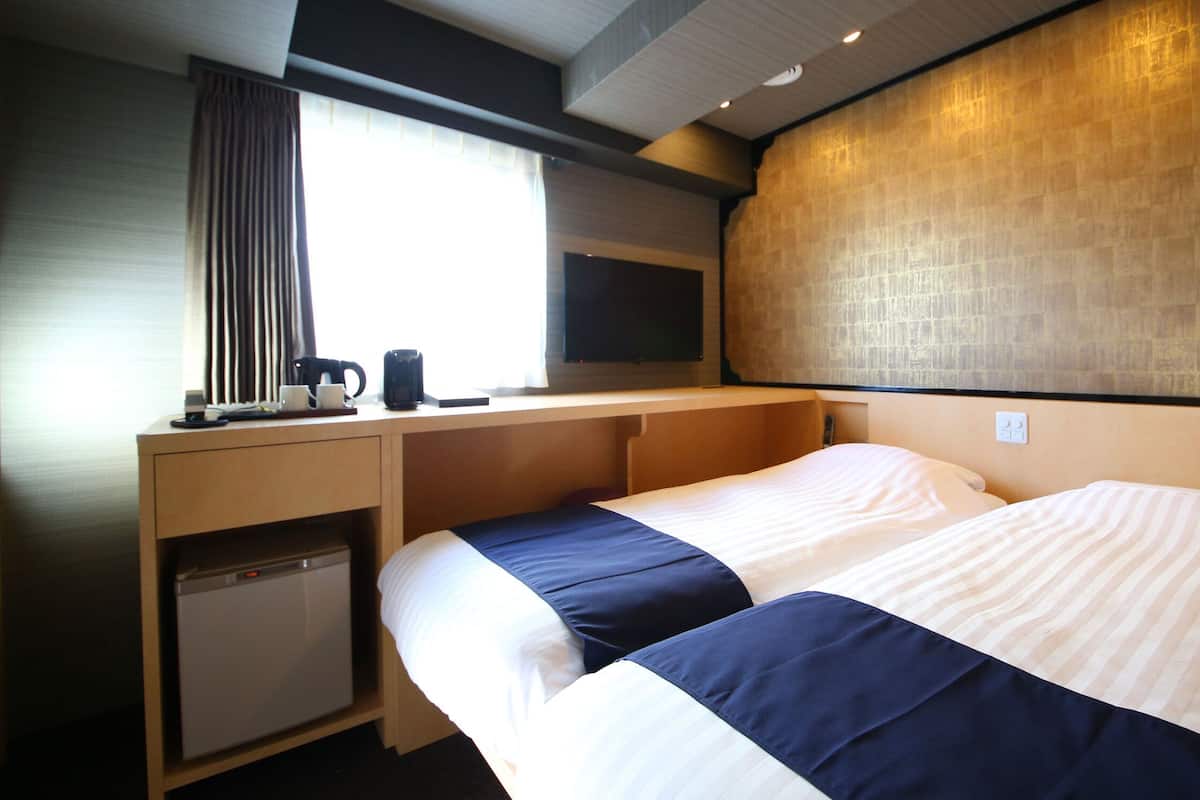 Een hotelkamer met een bed, een bureau, een koffiezetapparaat en een televisie.