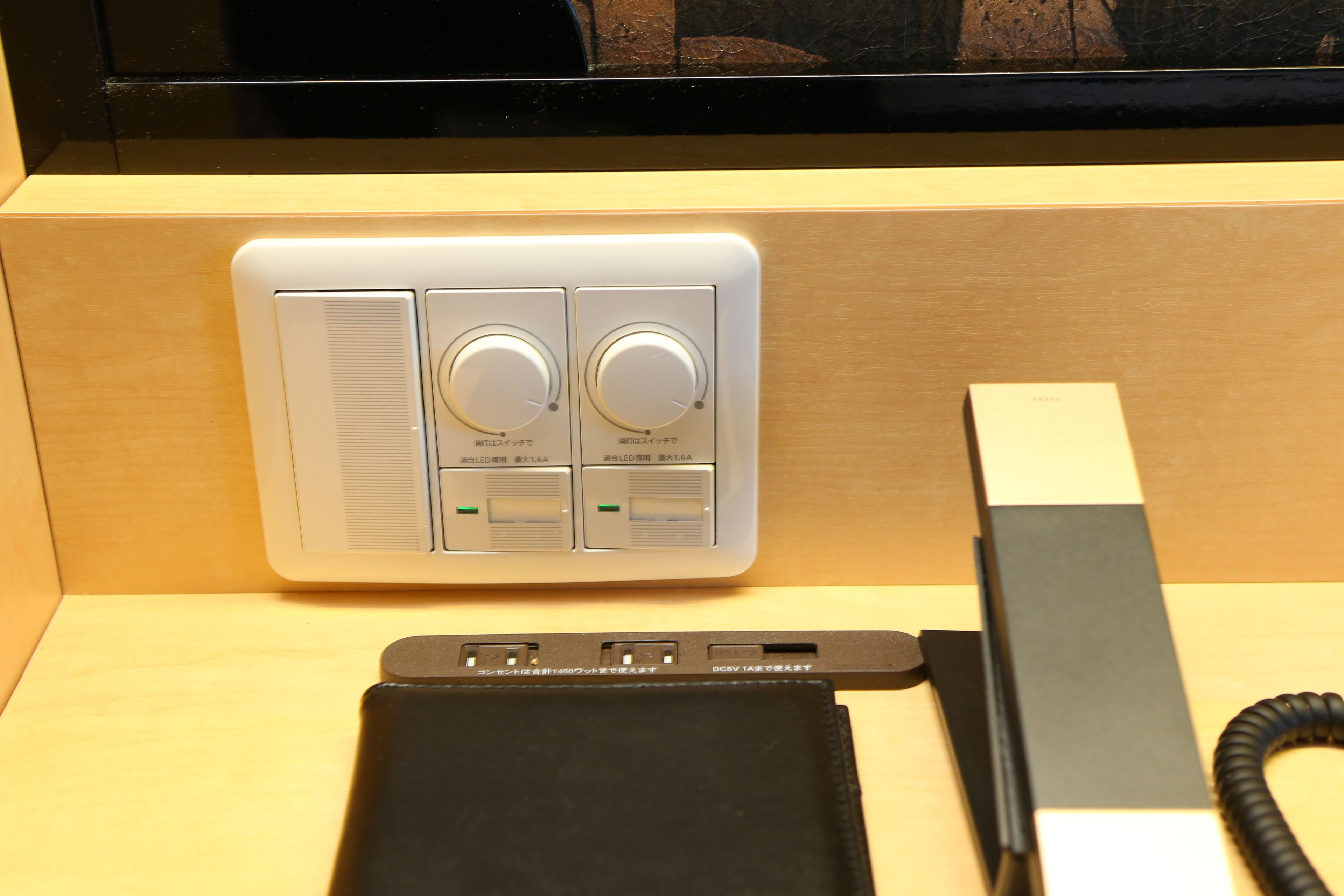 A control panel with two knobs and a power strip with a phone charger.
