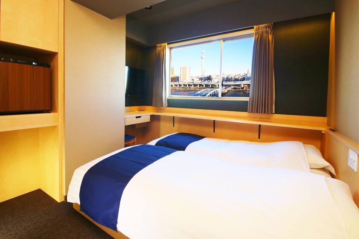 Hotelkamer met een bed, bureau, televisie en raam met uitzicht over de stad.