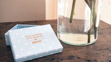 A glass vase with water and rose stems, and a blue box with heart patterns and text.