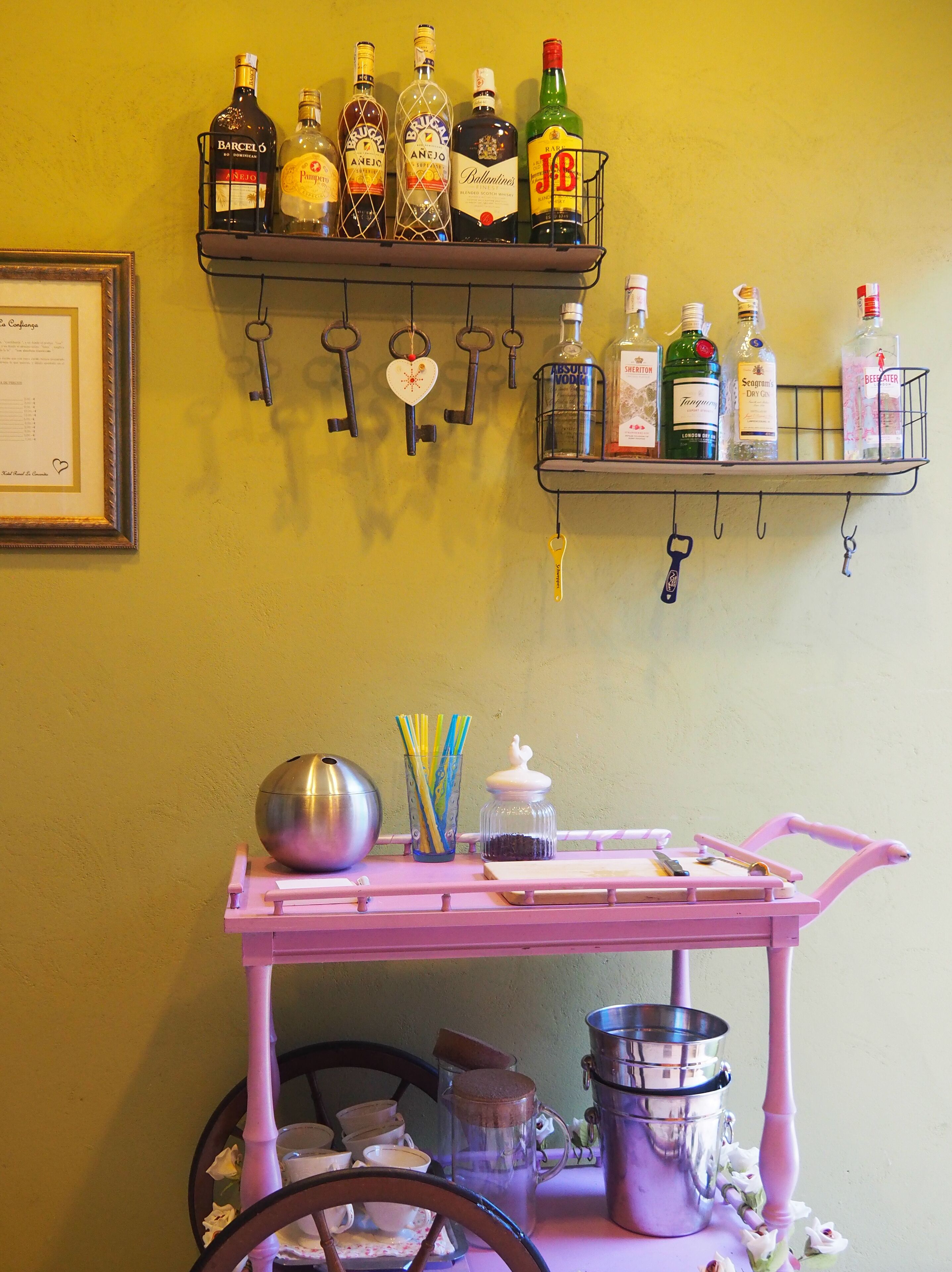 Un chariot à boissons avec des bouteilles et un porte-clés fixé au mur.