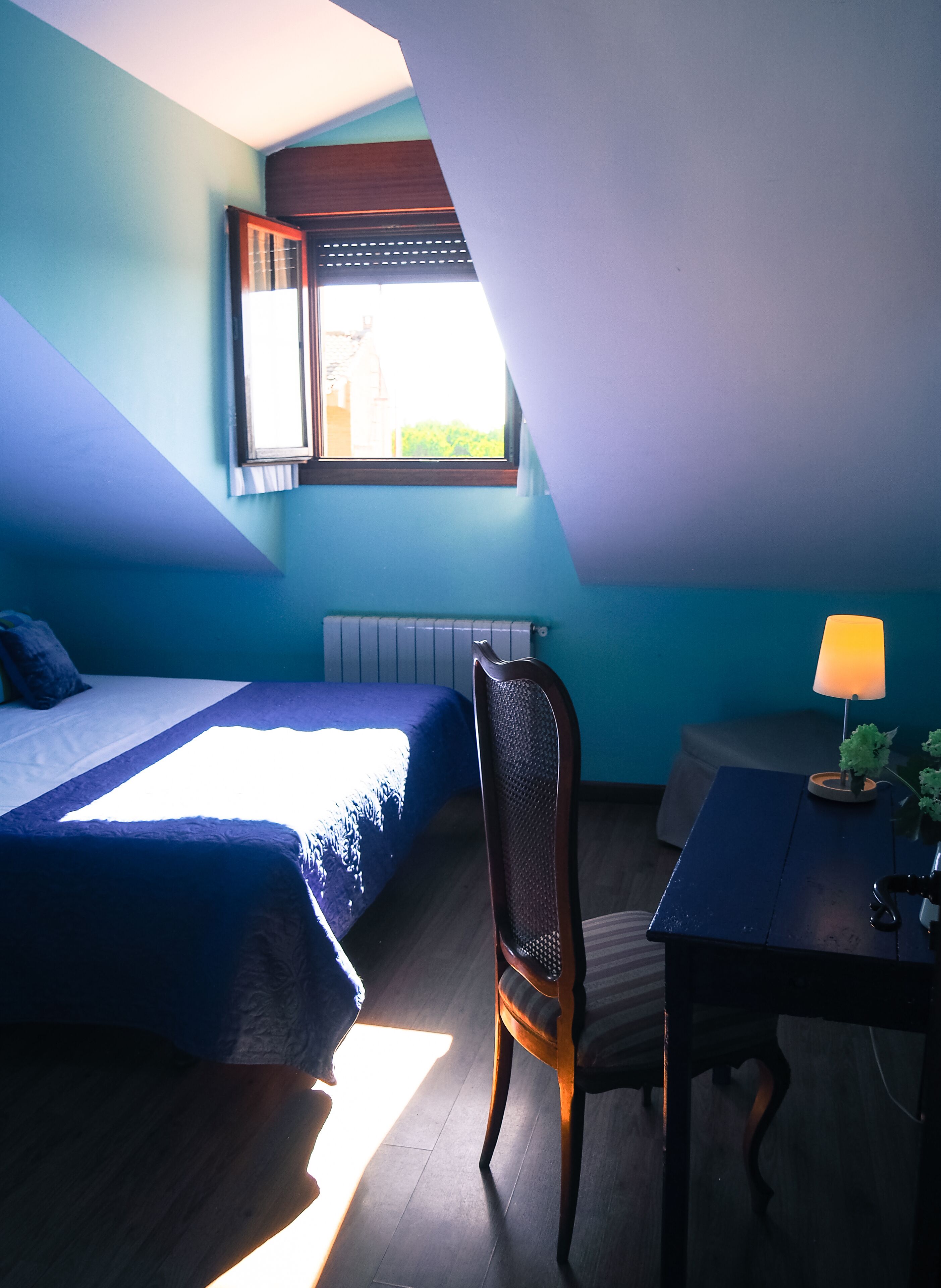 Una habitación con cama, una silla, una mesa y ventana.