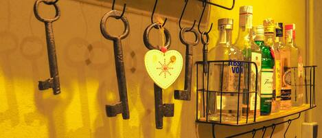 Una repisa montada en la pared con varias botellas de licor y un adorno con forma de corazón.
