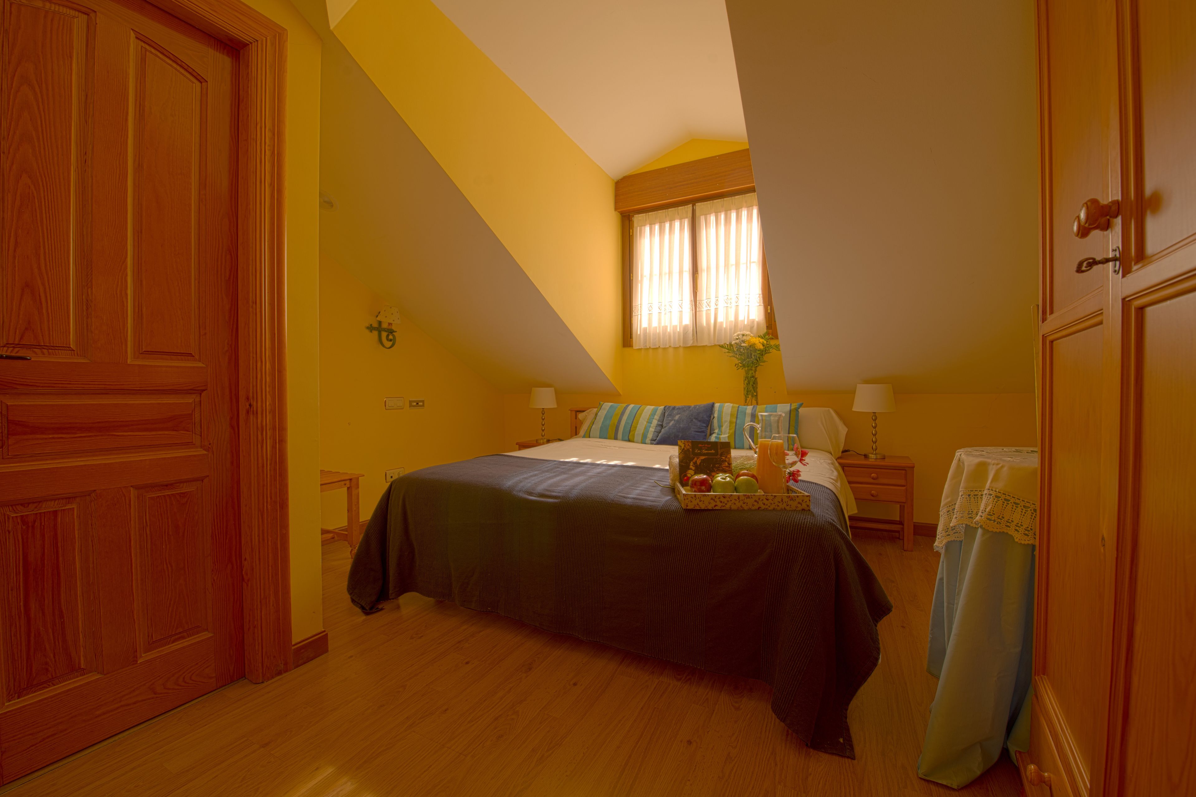 Une chambre à coucher avec un lit, une table de chevet, une lampe et une fenêtre avec des rideaux.