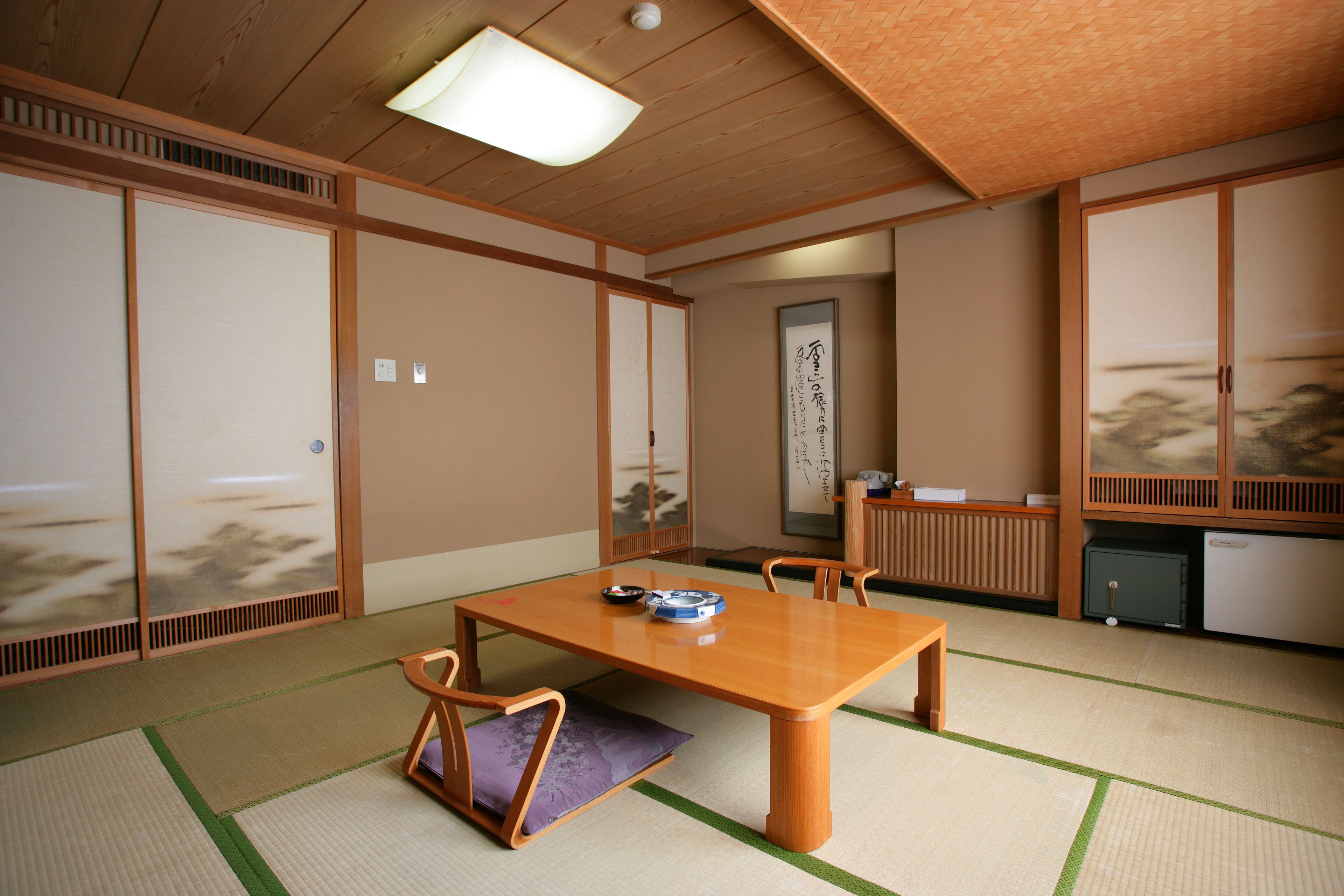 A traditional Japanese room with tatami flooring, a low wooden table, and sliding doors.