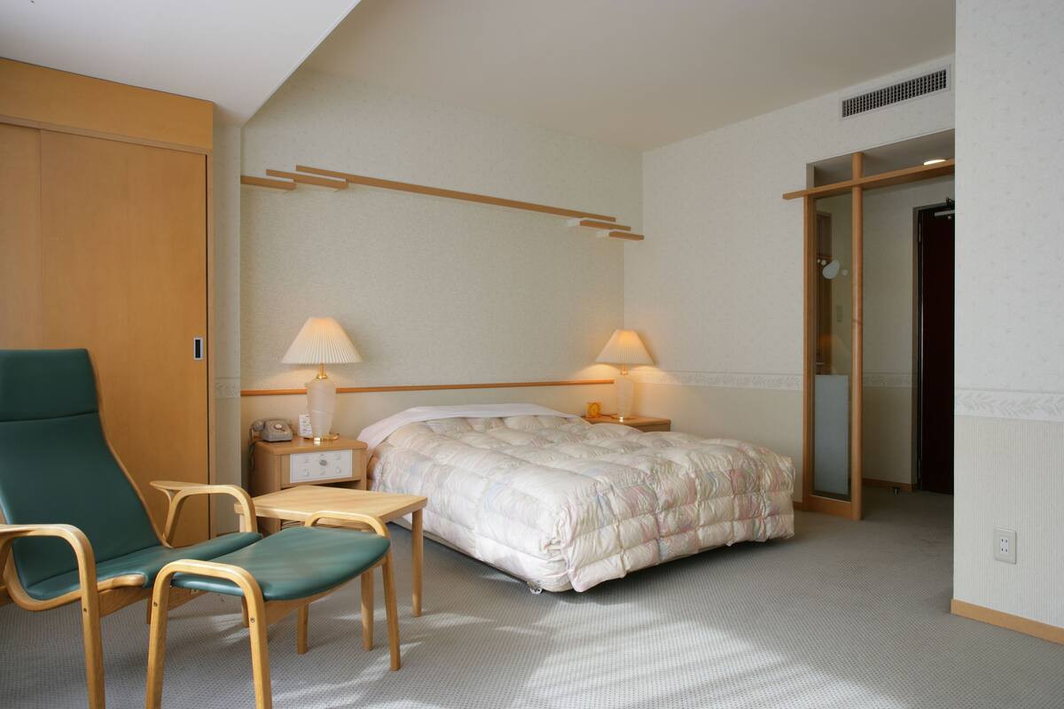 A bedroom with a bed, bedside tables, a chair, and a desk.