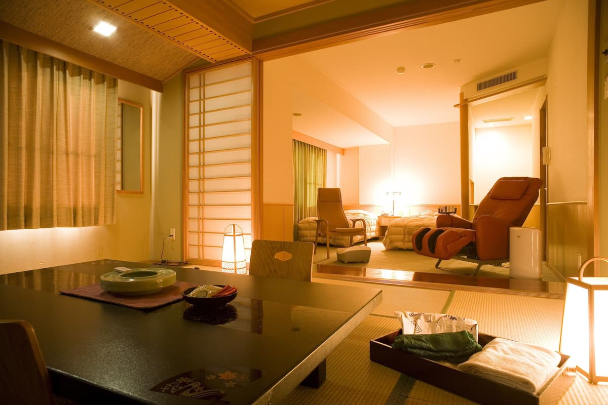 A traditional Japanese-style room with tatami flooring, a low table with a bowl and chopsticks, and a futon bed.