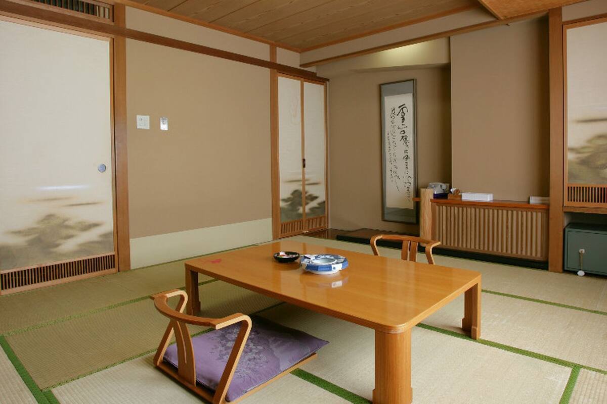 A traditional Japanese room with tatami flooring, a low wooden table, and sliding doors.