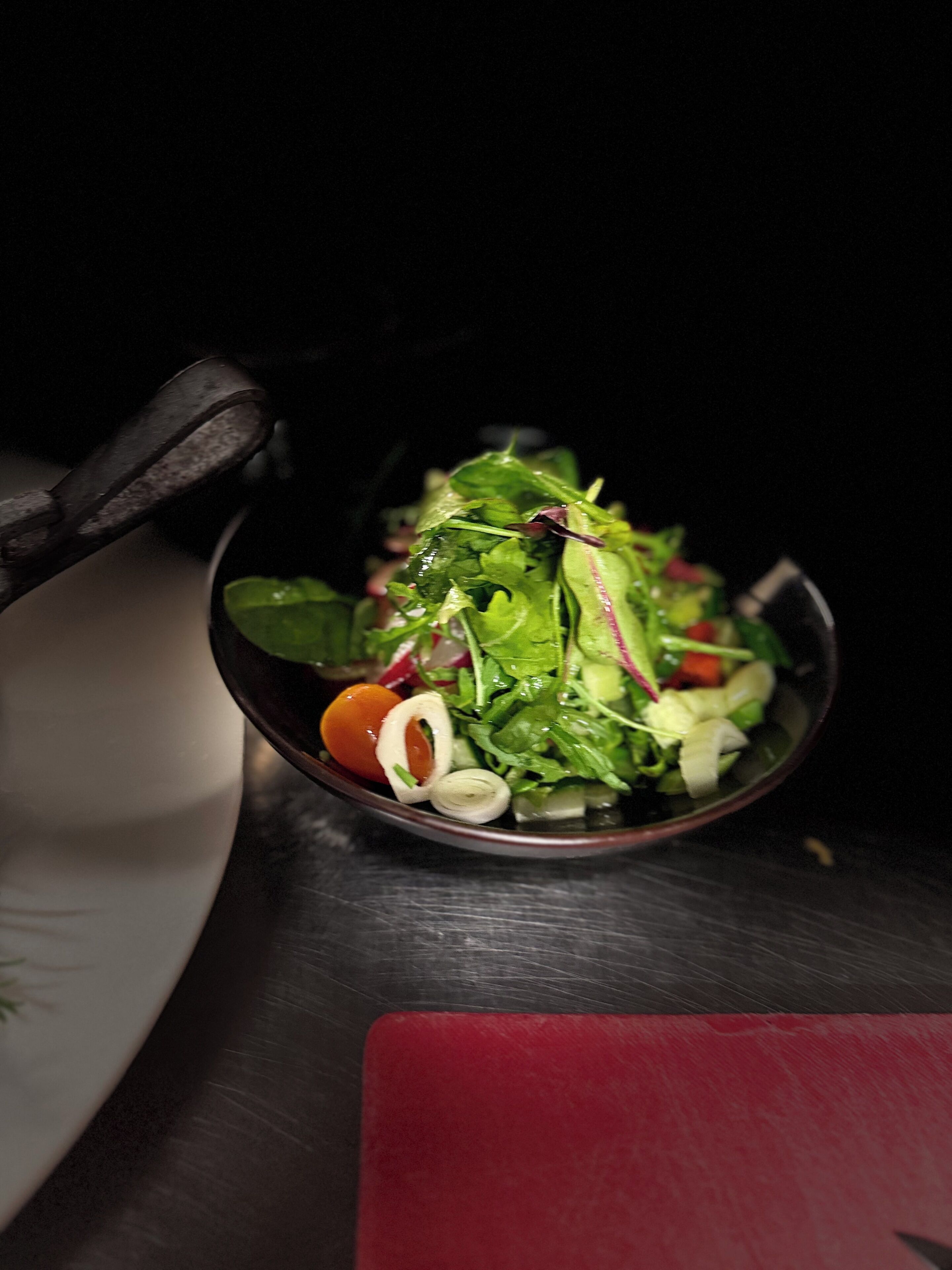 A bowl of salad with various greens and vegetables.
