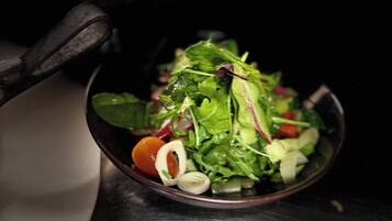 A bowl of salad with various greens and vegetables.