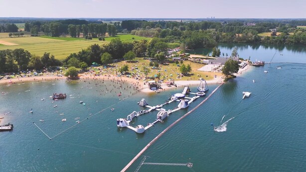 An aerial view of a lakeside area with boats, a dock, and a beach.