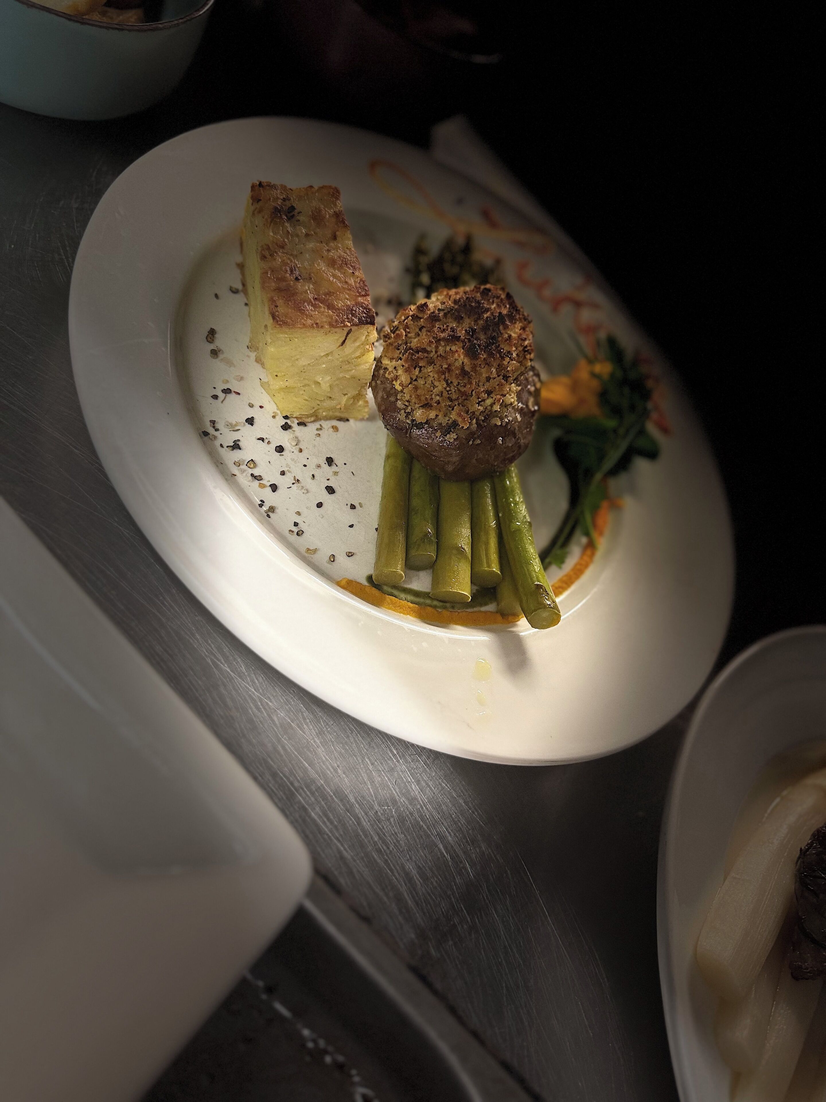 A plate with a piece of bread, a grilled item, and green vegetables.