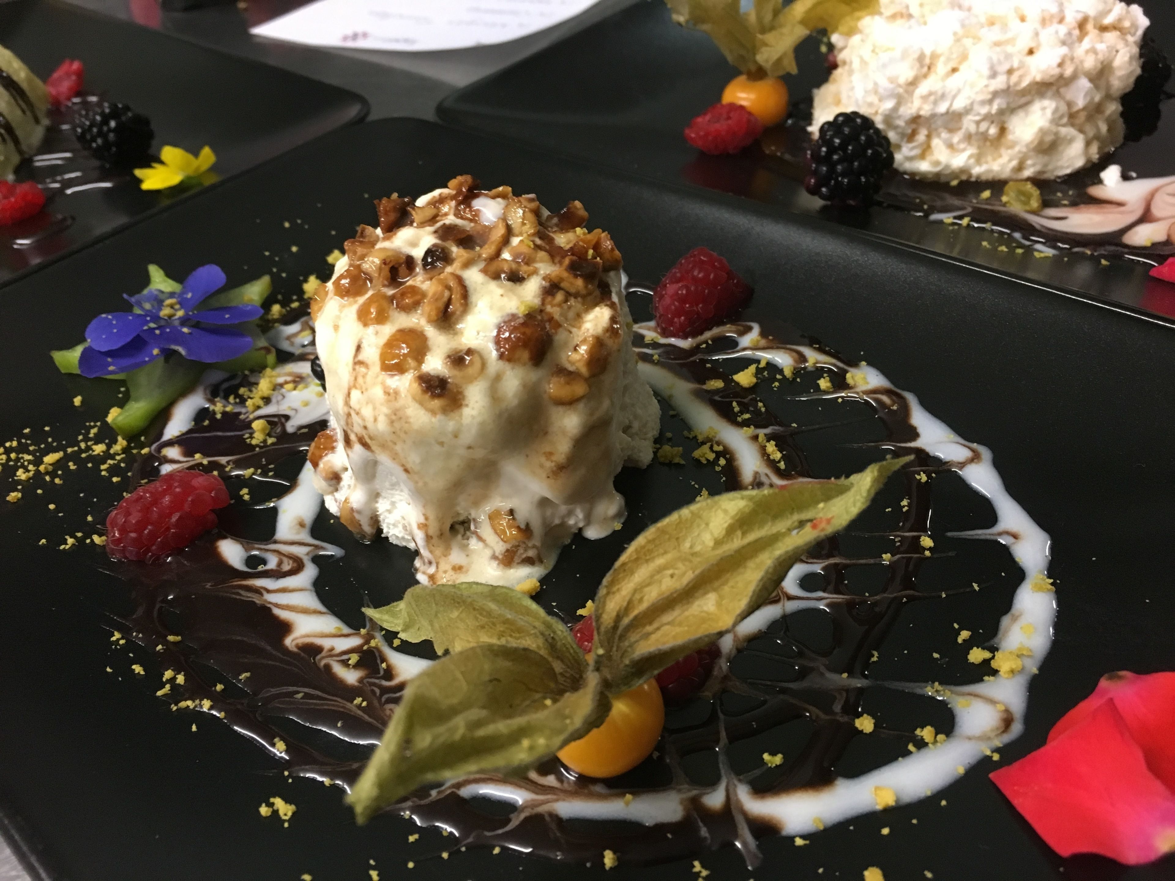 Un postre con frutos secos y bayas sobre un plato negro.