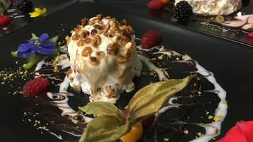 Un postre con frutos secos y bayas sobre un plato negro.