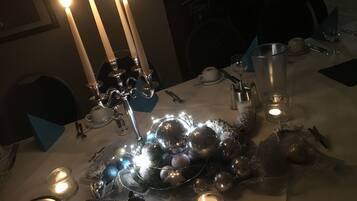Una mesa preparada para una comida, con velas, una jarra de vidrio y un centro de mesa decorativo.