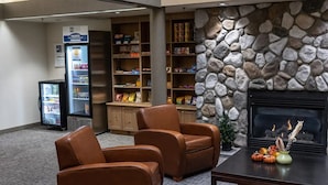 A lobby with leather armchairs, a stone wall, a fireplace, and a snack bar.