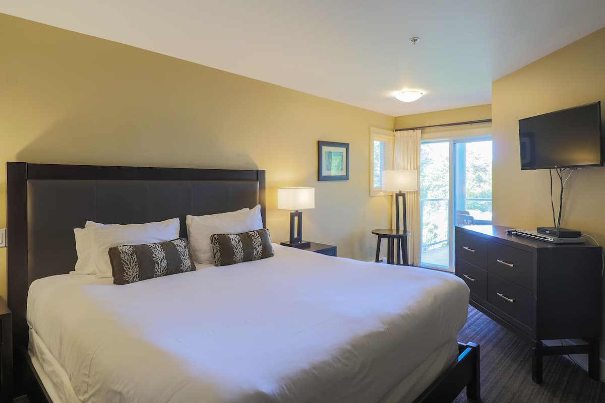 A hotel room with a large bed, a TV, a desk, and a window with a view.