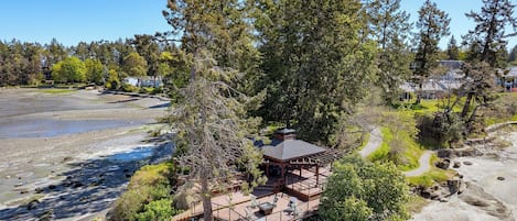 Une terrasse en bois avec des sièges extérieurs, entourée d’arbres et offrant une vue sur la plage.