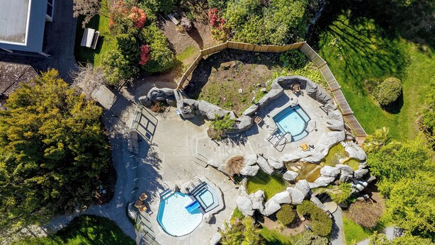 An aerial view of a property with two swimming pools surrounded by rock formations and greenery.