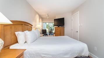 Une chambre d’hôtel dotée d’un grand lit, d’une tête de lit en bois, d’un téléviseur à écran plat et offrant une vue sur l’extérieur grâce à une porte vitrée.