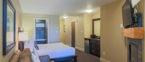 Une chambre d’hôtel comprenant un lit, un canapé, une télévision, une cheminée et un bureau.