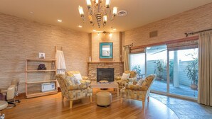 A spacious living room with a fireplace, comfortable seating, and a large sliding glass door leading to an outdoor area.