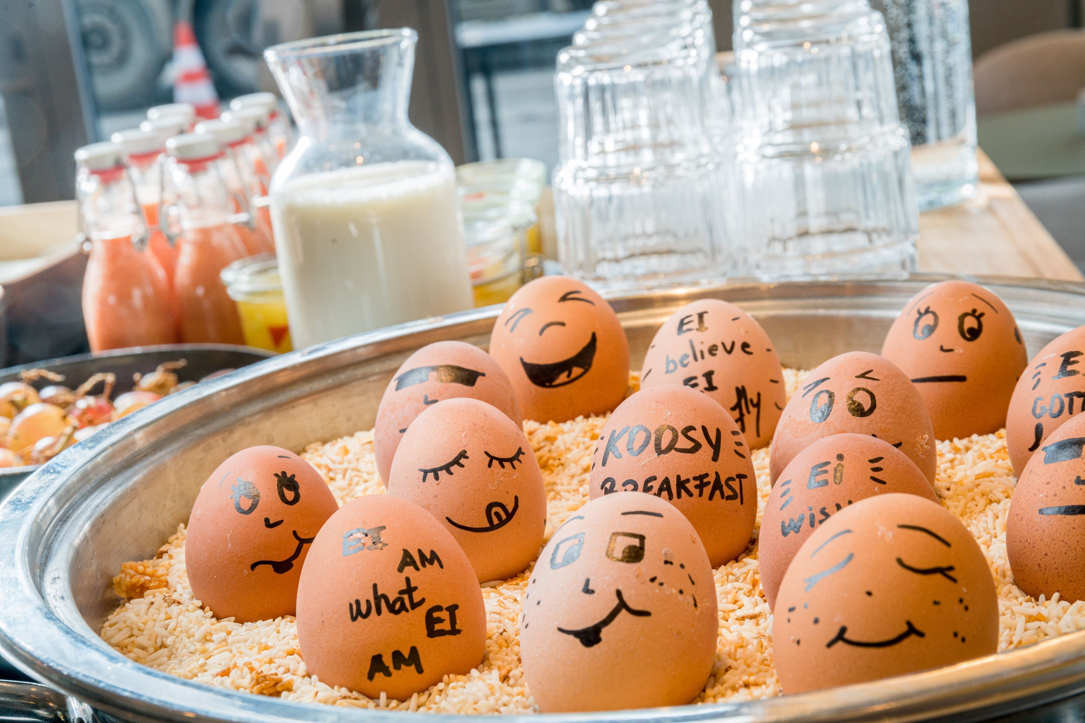 A tray of decorated eggs with faces and messages, surrounded by milk bottles and glasses.