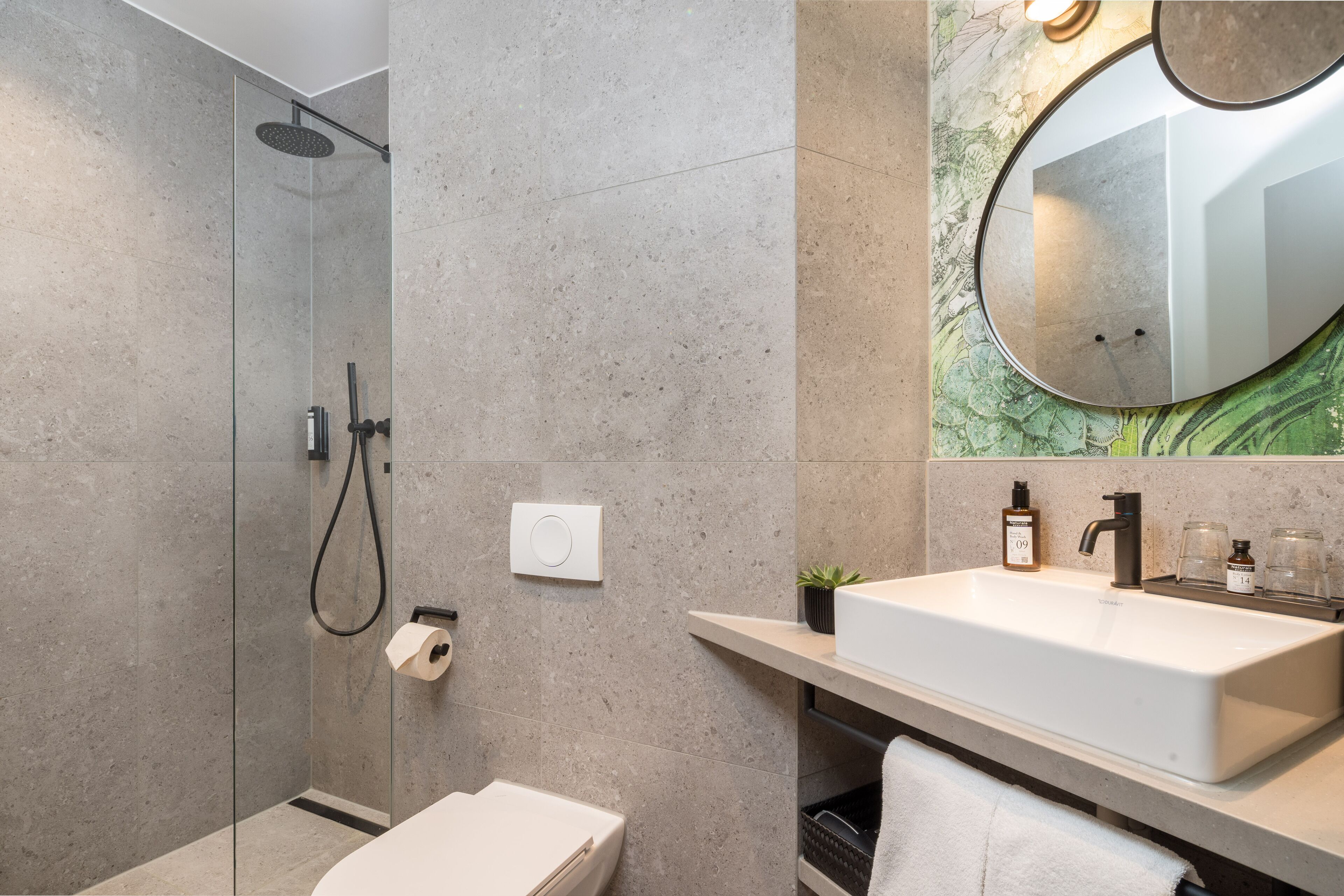 A modern bathroom with a glass-enclosed shower, a white sink, and a large mirror.