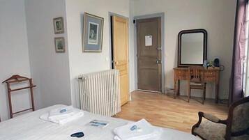 A hotel room with a bed, a wooden dresser, a mirror, and a radiator.