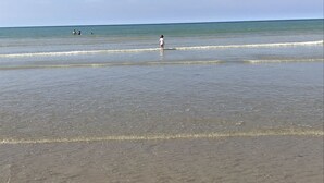 A beach with clear water and a person standing in the shallow water. - Auberge du vieux puits (Dieppe)