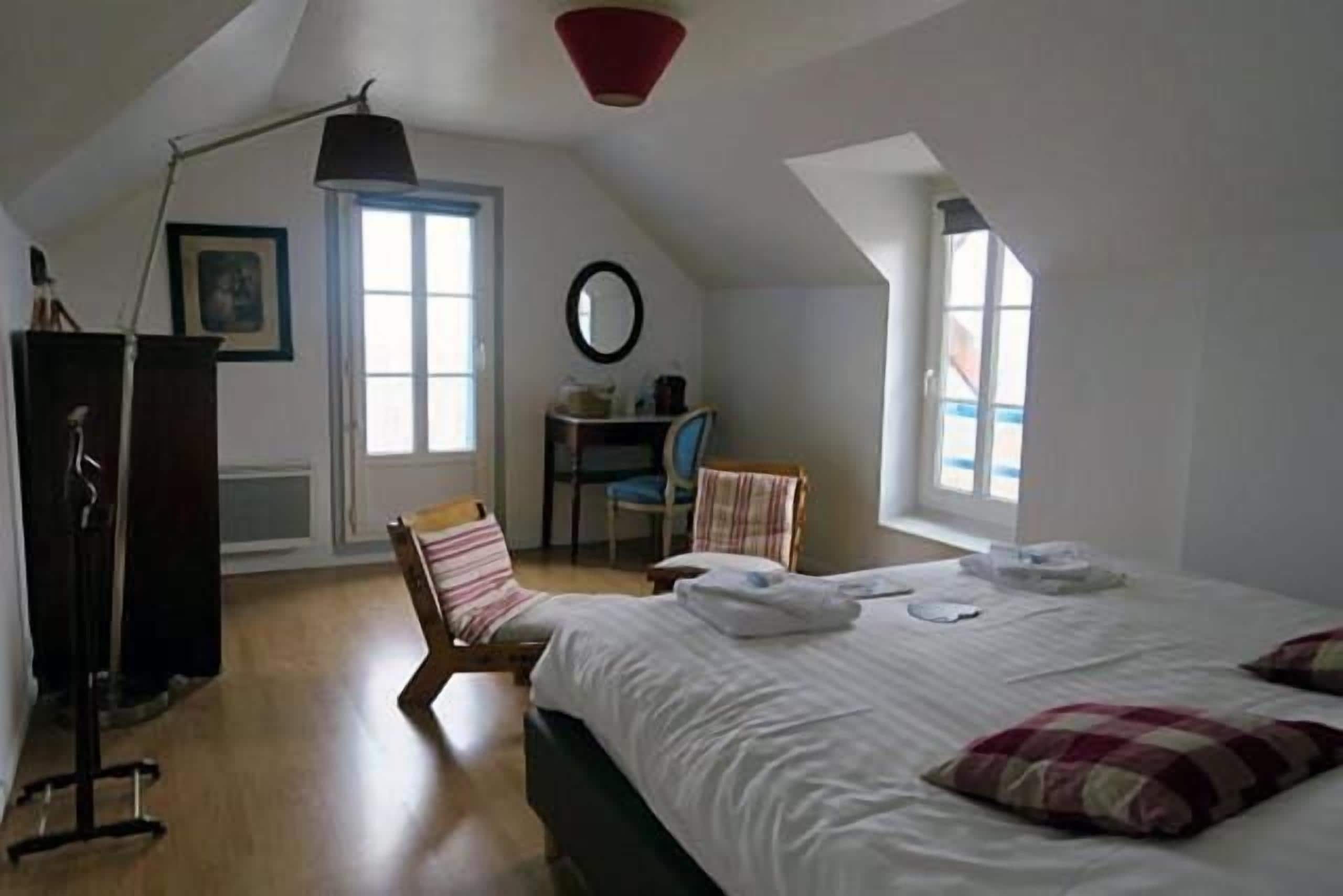 A bedroom with a bed, a desk, and a chair. There is a window and a door.