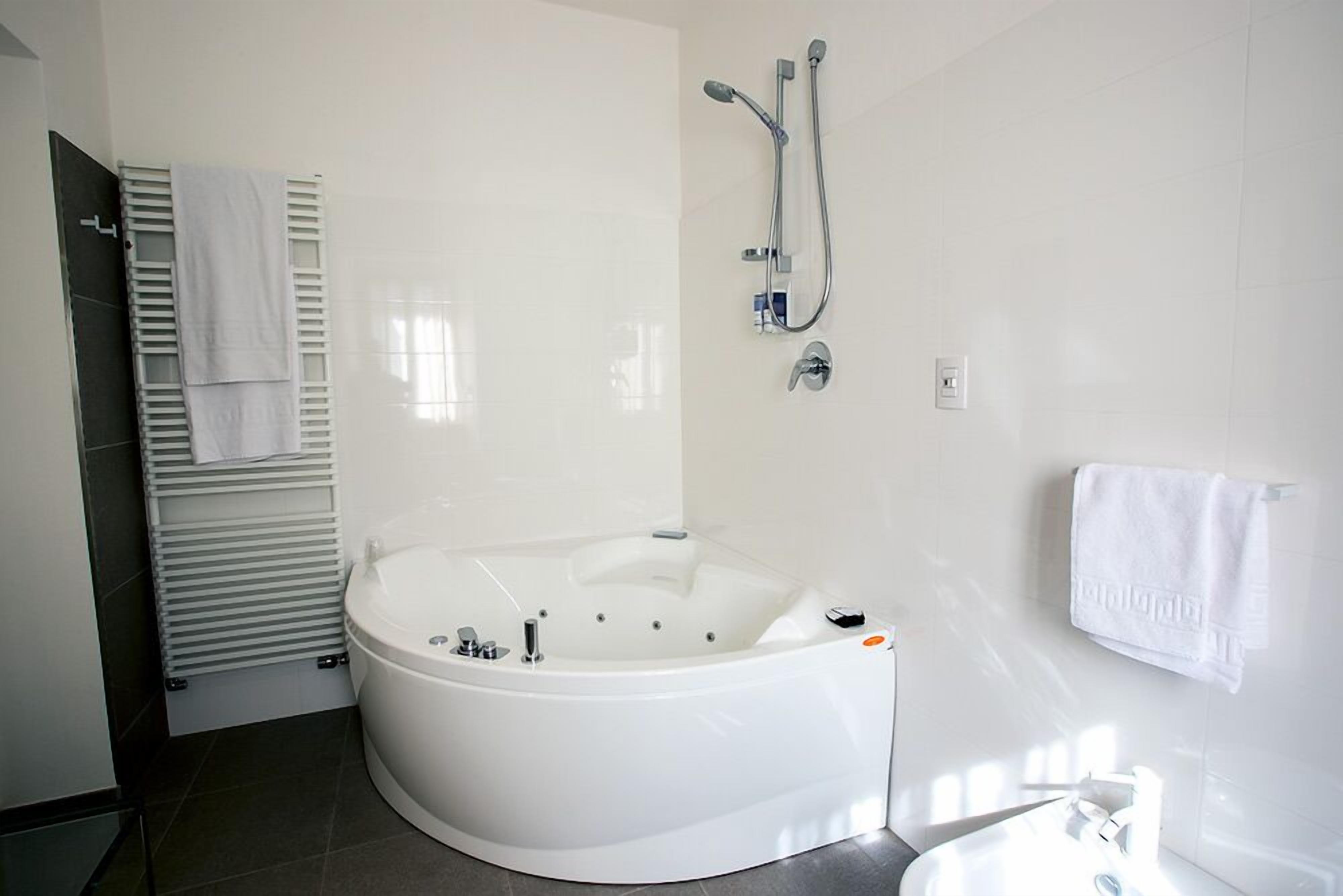 Un baño moderno con una bañera independiente, un cabezal de ducha y un perchero para toallas.