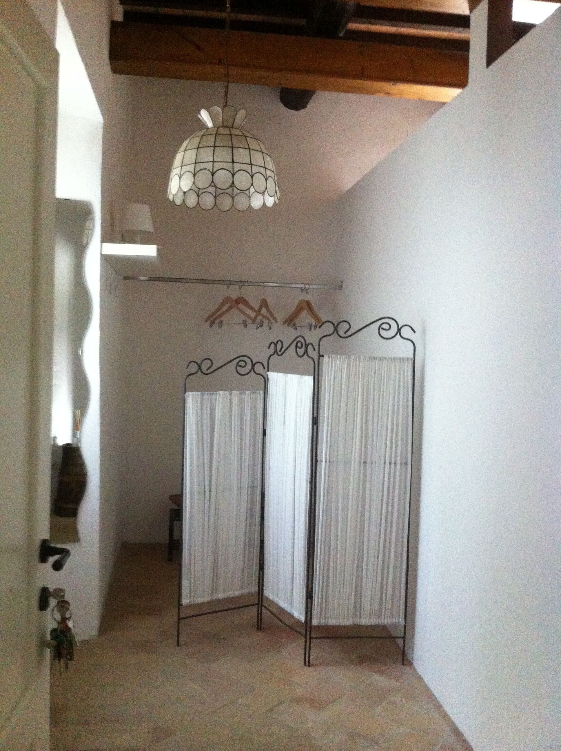 A hallway with a hanging light fixture, a radiator, and a partition with curtains.