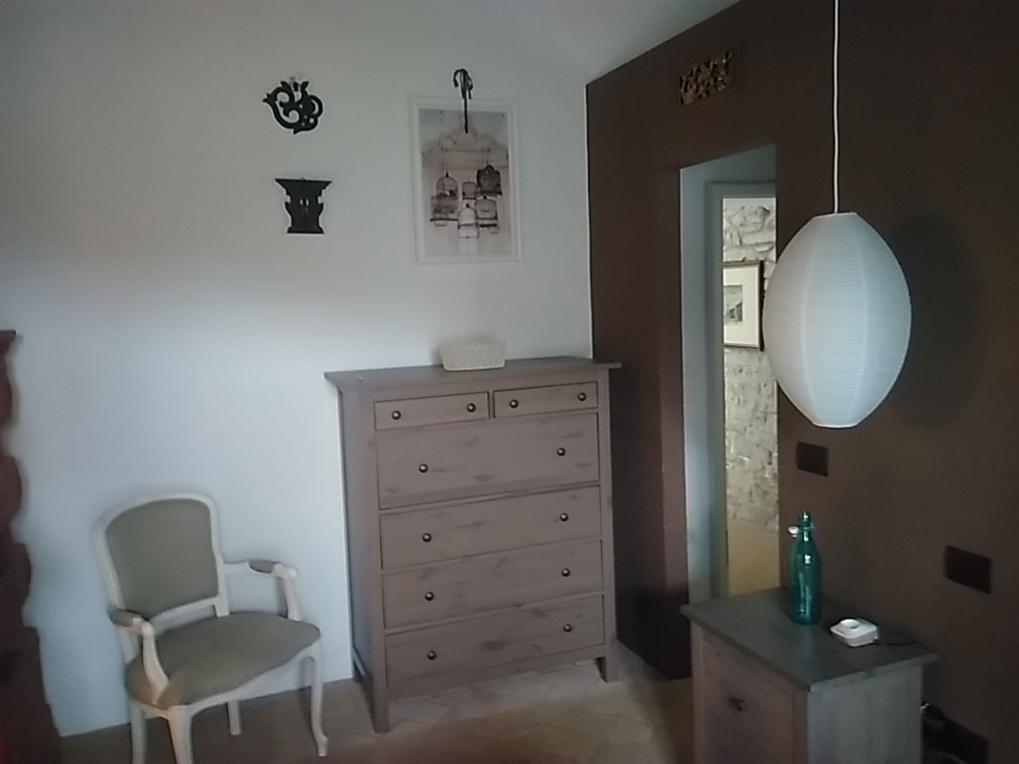 Una habitación con un aparador de madera, una silla y una lámpara colgante.