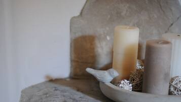 Un mur de pierres, des bougies et une statuette d’oiseau posés sur une table.