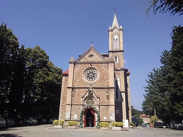 A church with a tall tower and a large circular window. - Corte San Ruffillo-Azienda Agrituristica (Dovadola)