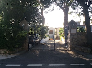 A gated entrance with a stone wall and a gate, leading to a building with a white facade and arched windows. - Hotel Victoria Place (Anacapri)