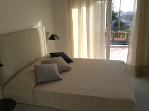 A bedroom with a large bed, a lamp, and a view of a balcony with plants. - Hotel Victoria Place (Anacapri)