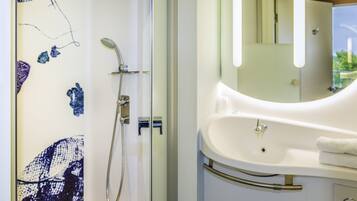 A bathroom with a shower, a sink, and a mirror.