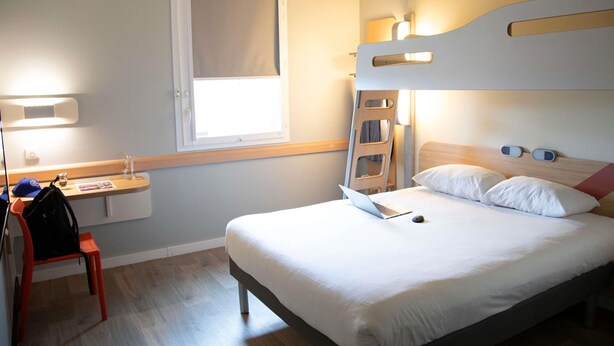 A hotel room with a bunk bed, a desk with a laptop, a chair, and a window. - ibis budget Saint Quentin en Yvelines Velodrome (Montigny-le-Bretonneux)